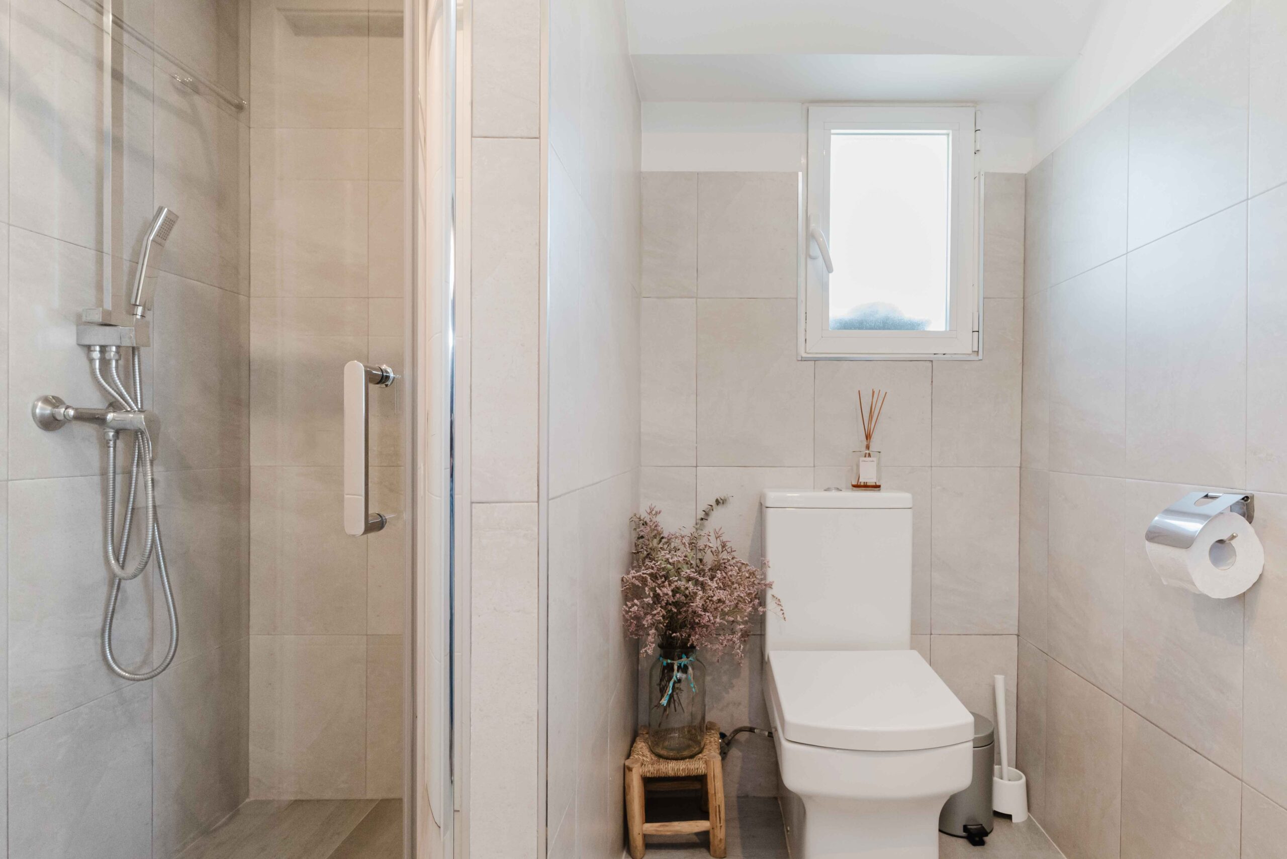 Baño con ducha, lavabo y acabados en tonos claros