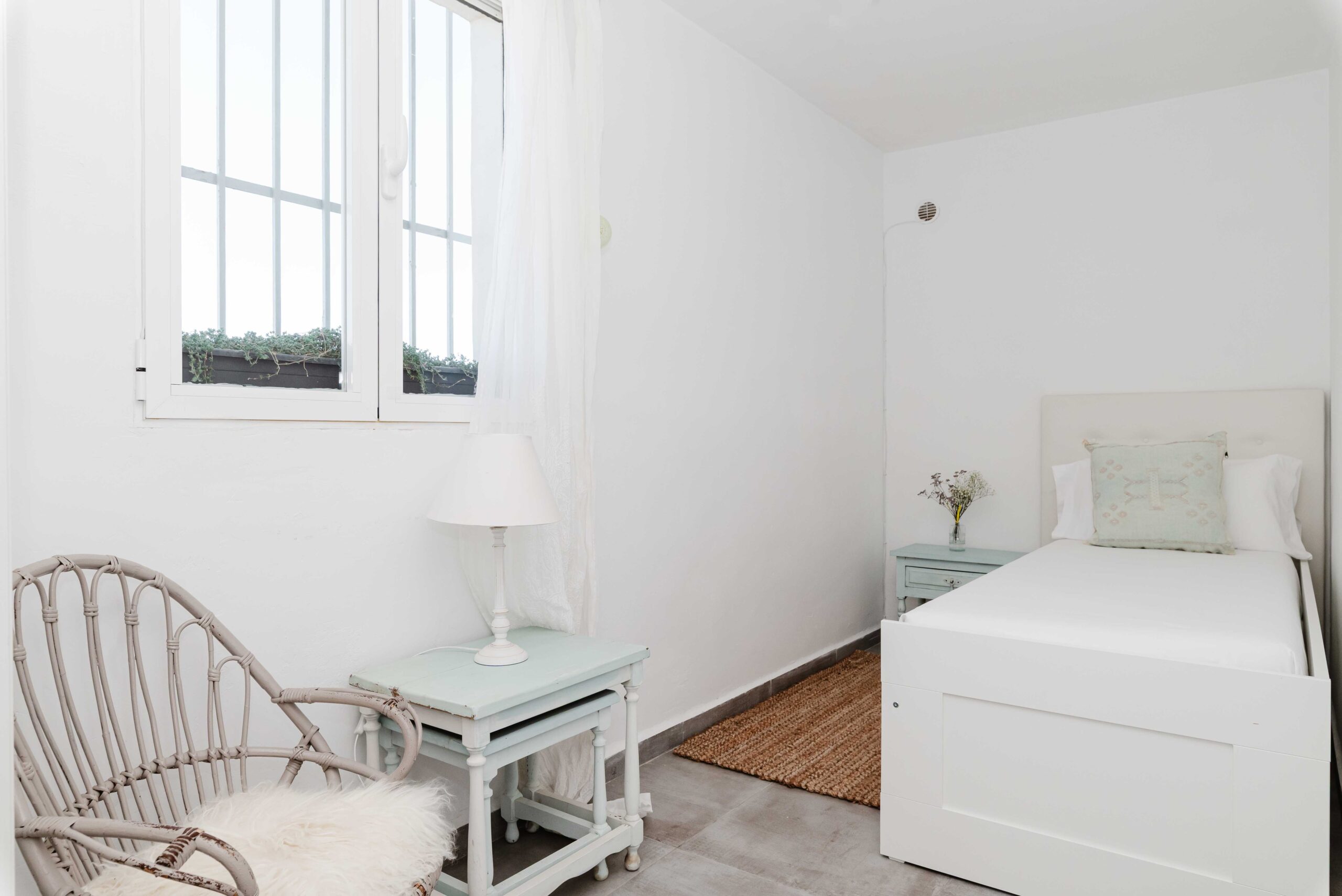 Dormitorio con cama, decoración en tonos claros y entrada de luz natural